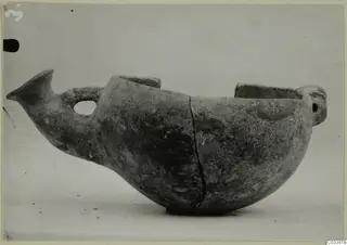 Red Polished III bowl from Lapithos with a pointed projection, loop handle and raised lugs, seen from the side.