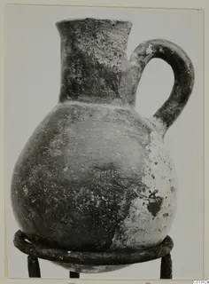 Red Polished III jug from Lapithos, Vrysi tou Barba tombs, standing on a metal ring stand