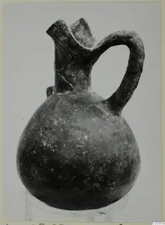 Pottery Red Polished III jug with a rounded body, flared spout and strap handle