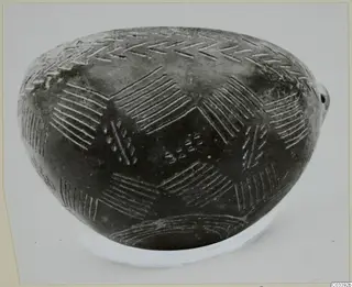 Pottery Red Polished III bowl from Lapithos with incised chevron and hatched patterns on a dark surface.