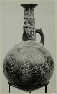 Red Polished II jug with a tall flared neck, two applied ridges on the neck, and a single loop handle, shown on a metal stand.