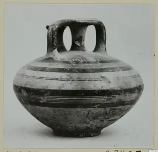 Round-bodied pottery jar with a broad loop handle over the mouth and horizontal painted bands on the body.