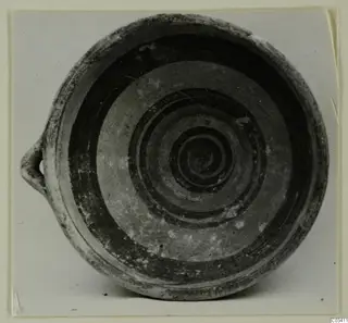 Bowl-jar with a single loop handle, its interior decorated with dark concentric and spiral bands.