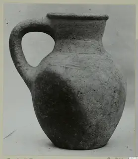 Pottery Plain White Wheel-made jug from Enkomi, with a single loop handle and a flared rim.