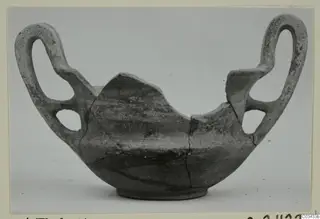 Broken pottery bowl with two large loop handles, shown against a plain grey background.