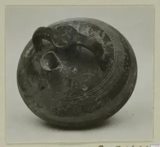 Dark grey pottery bowl-jar with a loop handle and small spout, with incised lines around the body