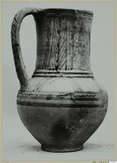Bichrome painted jug with a tall strap handle and a flaring rim, photographed against a plain background.