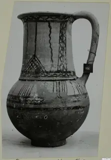 White Painted wheel-made jug with a strap handle, dark banded and hatched decoration on the neck and body