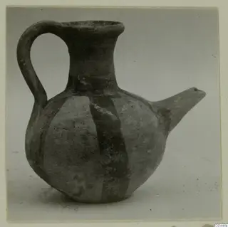 Round-bodied jug with a strap handle, a spout and a wide mouth, decorated with broad painted bands, photographed against a grey backdrop.