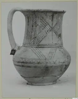 White painted wheel-made jug with a long loop handle and cross-hatched bands of decoration.