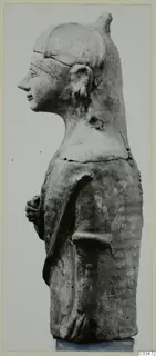 Terracotta Neo-Cypriote figure seen in profile, facing left, with a tall headdress and hands held at the waist