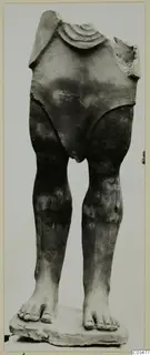 Terracotta figure with head and arms missing, standing on a flat base, legs and feet intact