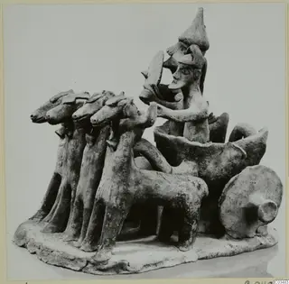 Terracotta model of a vehicle drawn by four animals, with two standing figures, on an oval base