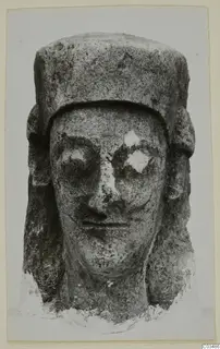 Limestone head sculpture seen from the front, with a flat-topped headdress and side locks