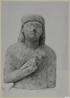 Limestone bust of a woman with her right hand resting on her chest, head covered by a band.