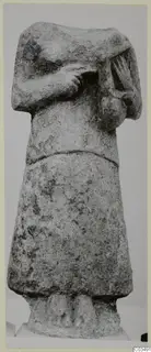 Headless limestone statue of a standing figure with arms bent across the chest.