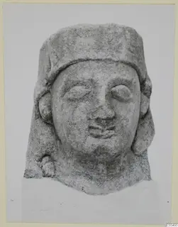 Limestone Proto-Cypriote head, front view, with a flat-topped headdress and hair falling to the shoulders