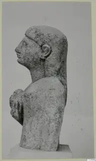 Limestone sculpture of a head and upper body in profile, facing left, with one arm bent up to the chest.