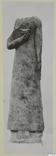 Limestone statue of a standing figure with one arm raised towards the face, on a rectangular base