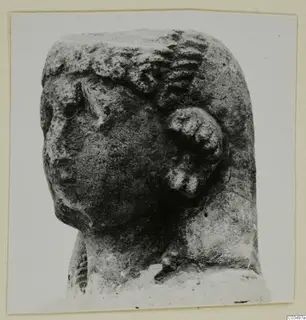 Limestone sculpture of a head, photographed in three-quarter view with a worn face on the left.
