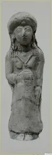 Terracotta figurine of a standing female figure with a tall headdress and curled hair, photographed against a grey background.