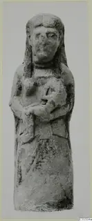 Terracotta figurine of a standing figure with long hair, arms bent across the chest, holding a small rounded object.