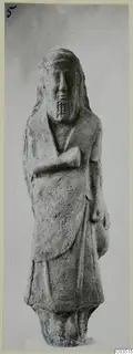 Standing figure with long hair and a short incised beard, one arm folded across the chest, against a plain grey background