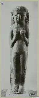 Standing female figurine with hands resting on its breasts and hair framing the face