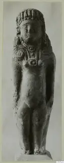 Terracotta standing figurine with a curled headdress and necklace, seen from the front.