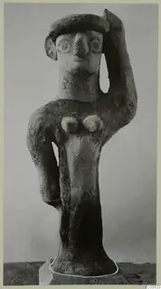 Terracotta figurine of a standing human figure with one arm raised to its head