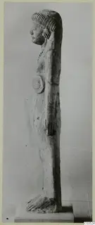 Side view of a standing terracotta figurine on a rectangular base