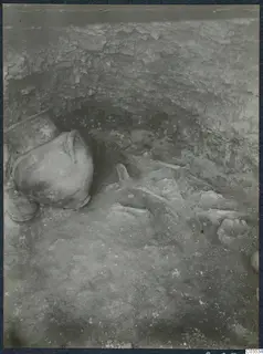 Excavation at Stylli showing a large jug on the left and scattered bones and a small bowl on the floor of the cut