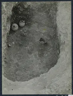 Excavated pit at Stylli with several small pots and a bowl lying in the soil floor