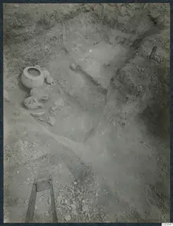 Excavation at Stylli with pottery vessels and broken sherds lying on the floor of a trench