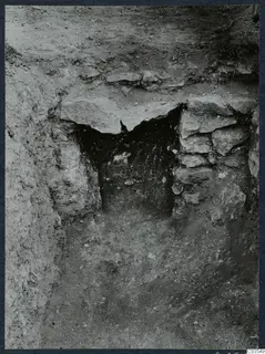 Excavation trench at Stylli with large flat stone slabs over a dark opening