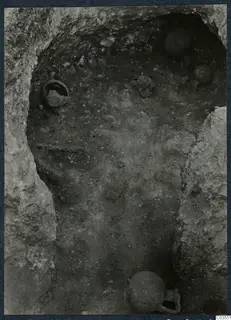 Excavation at Stylli showing several pots and objects lying on the floor of a cut chamber in the rock