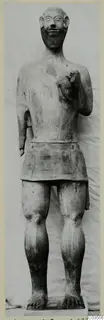Terracotta statue of a bearded standing figure from Ayia Irini, photographed against a draped light cloth