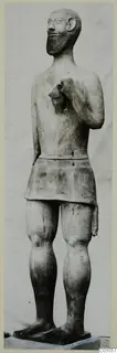 Terracotta statue of a standing bearded man in a short skirt, one hand raised to the chest.