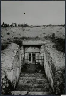 Built tomb entrance at the top of a stone-walled stepped passage, with an iron grille across the doorway