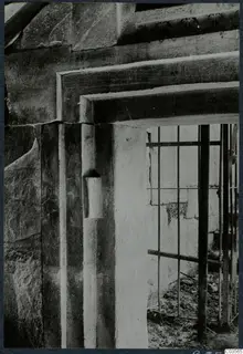 Doorway of a built tomb with a stone lintel and jamb, closed by an iron grille
