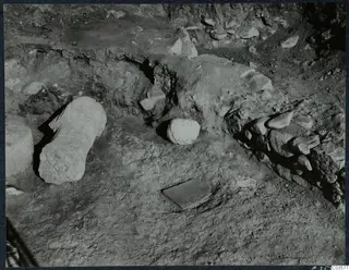 Finds in situ at Cholades, Soli: a long cylindrical stone block and rounded stones lying in excavated ground.