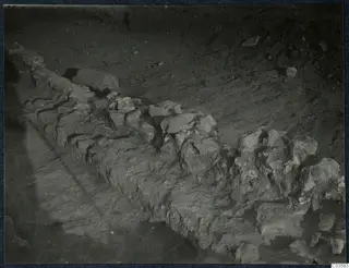 Excavated stone wall foundation running diagonally across bare soil at Soli, Cholades.