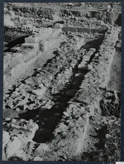 Excavation at Soli showing stone walls, stepped stone blocks and a narrow channel running between rows of stones.