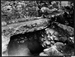 Excavated walls and large flat stone slabs at Soli, Cholades Temples A-B, with a dark recess beneath a slab.