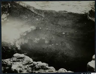 Excavation trench at Soli with a row of pale stones along one side and a layered soil section beyond
