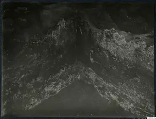 Close view of a rough stone surface with pale patches meeting at a V-shaped angle, Cholades, Soli