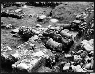 Excavation at Cholades, Soli, with low rubble walls and fallen column drums lying among scattered stones.