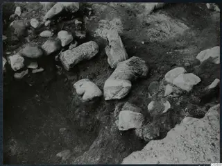 Excavation at Cholades, Soli, showing stone blocks, a cylindrical stone fragment and rubble in a dug trench.
