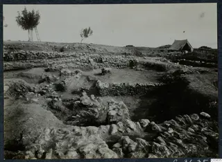 Excavated stone foundations at Soli, Cholades Temples A-B, with a tent and two trees beyond