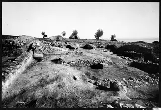 Excavated stone walls of Temple C at Cholades, Soli, seen from the south, with a tent and a grazing animal behind